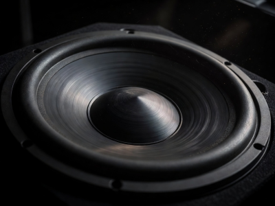 Close up of a large 15-inch subwoofer driver cone vibrating in a dark environment
